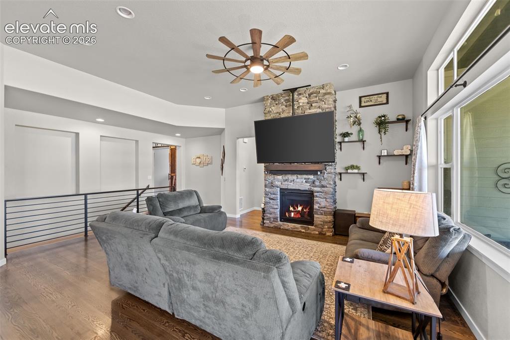 Image 9 of 32: Living area featuring a stone-clad fireplace with a wood mantel, wood-finis