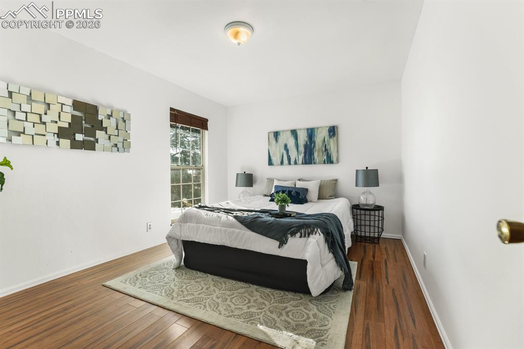 Image 17 of 28: Upper Level Primary Bedroom with wood laminate floor and view window with w