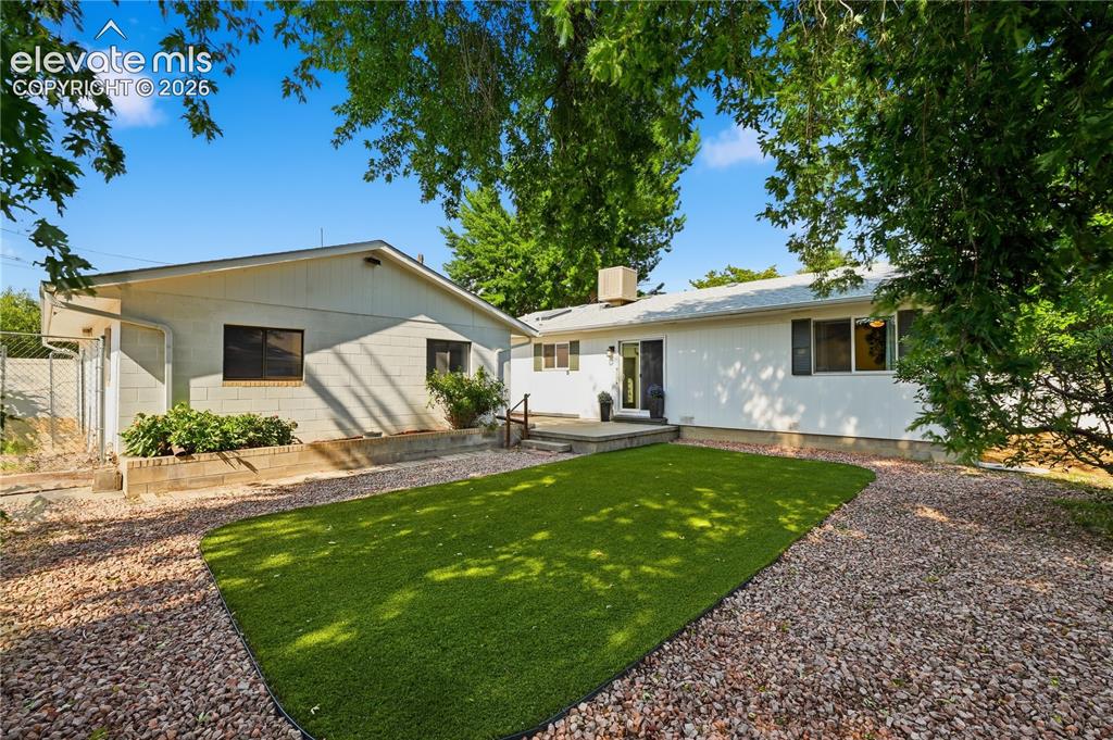 Image 21 of 27: Private fenced backyard featuring low maintenance artificial turf, mature t