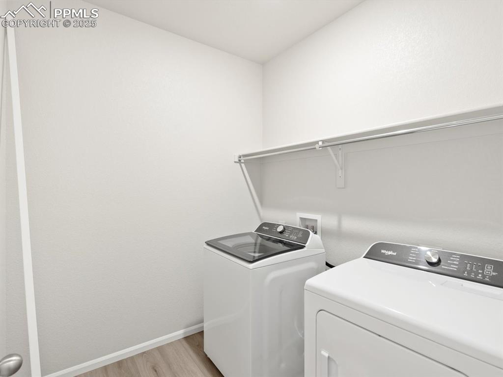 Image 13 of 19: Laundry room with washer and clothes dryer and light wood-type flooring