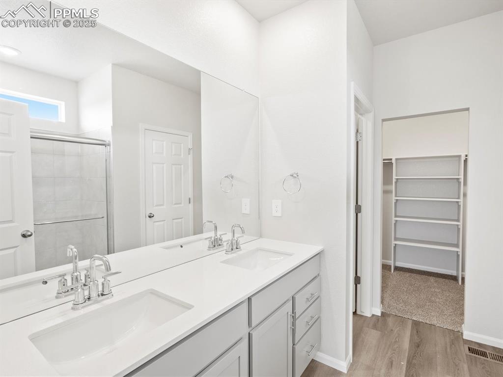 Image 15 of 19: Bathroom featuring double vanity, a stall shower, wood finished floors, and