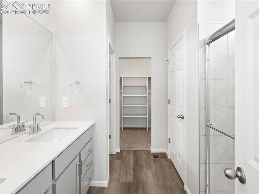 Image 16 of 19: Full bath with double vanity, wood finished floors, a spacious closet, and 
