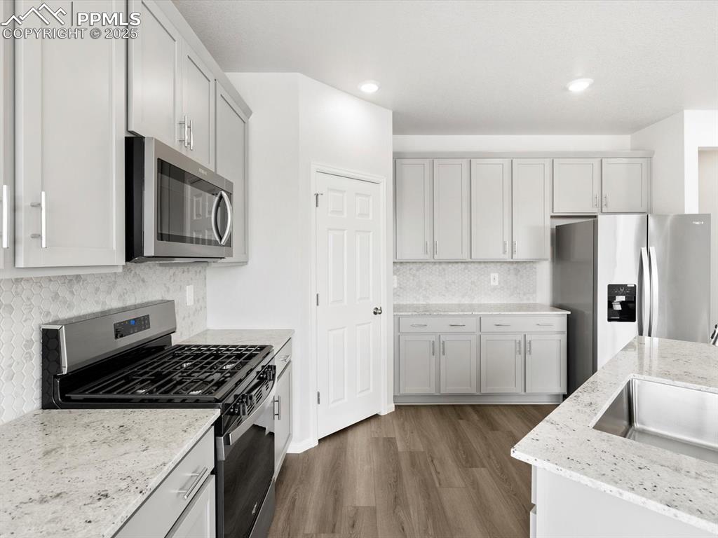Image 4 of 19: Kitchen featuring appliances with stainless steel finishes, wood finished f