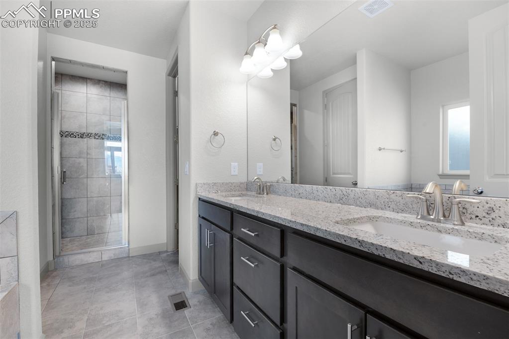Image 11 of 21: Bathroom with a stall shower, double vanity, and light tile patterned floor