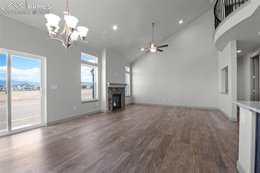 Image 8 of 21: Unfurnished living room with high vaulted ceiling, a stone fireplace, dark 