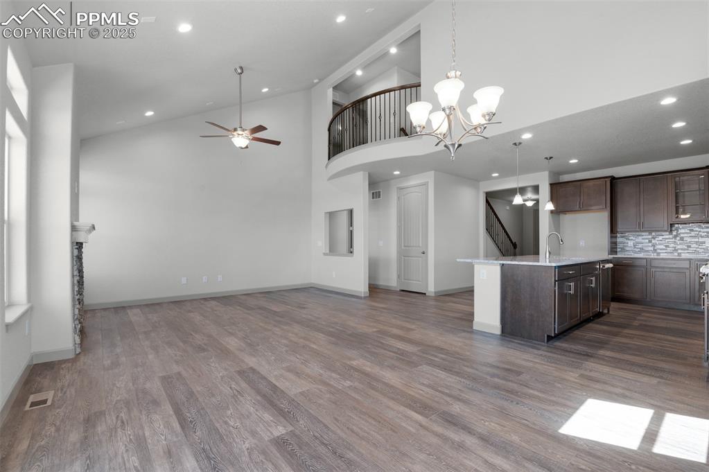Image 9 of 21: Kitchen featuring high vaulted ceiling, decorative light fixtures, dark bro