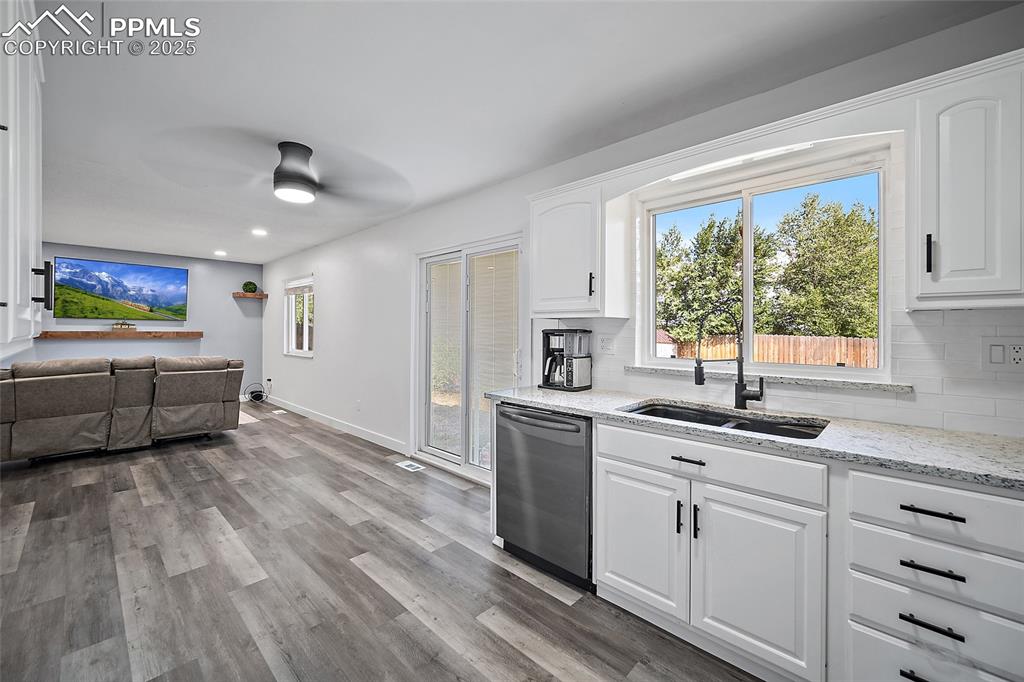 Image 10 of 38: Kitchen with light stone countertops, white cabinets, healthy amount of nat