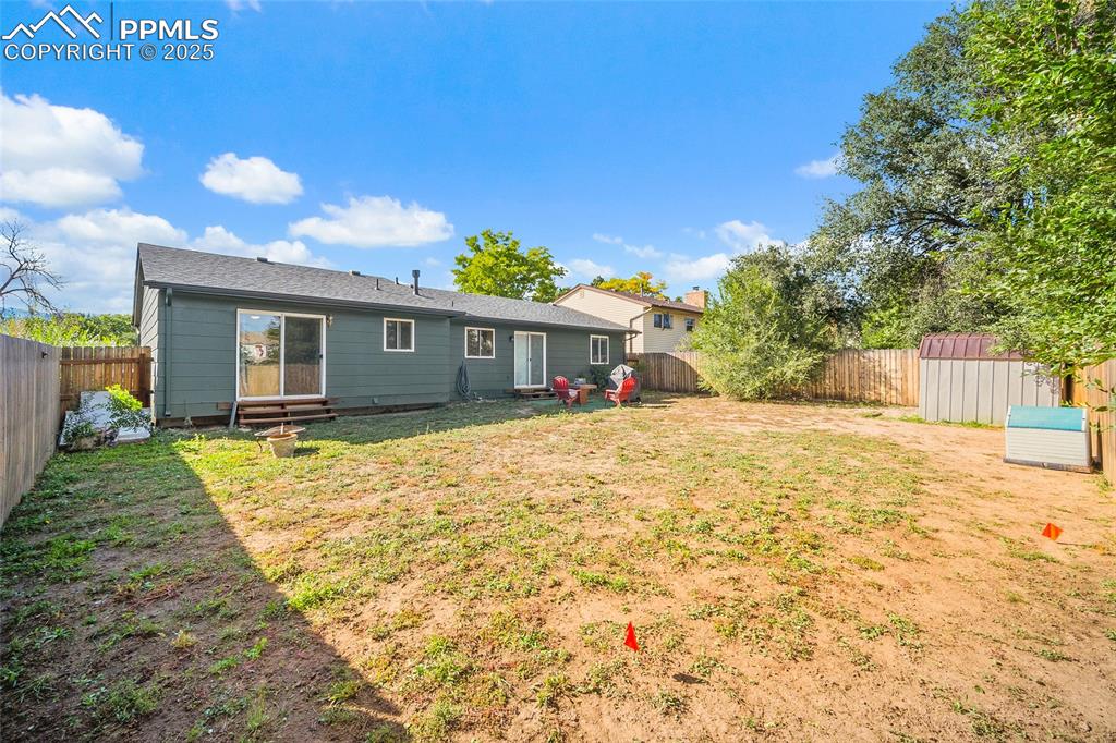 Image 25 of 38: Back of house with a fenced backyard and a storage shed