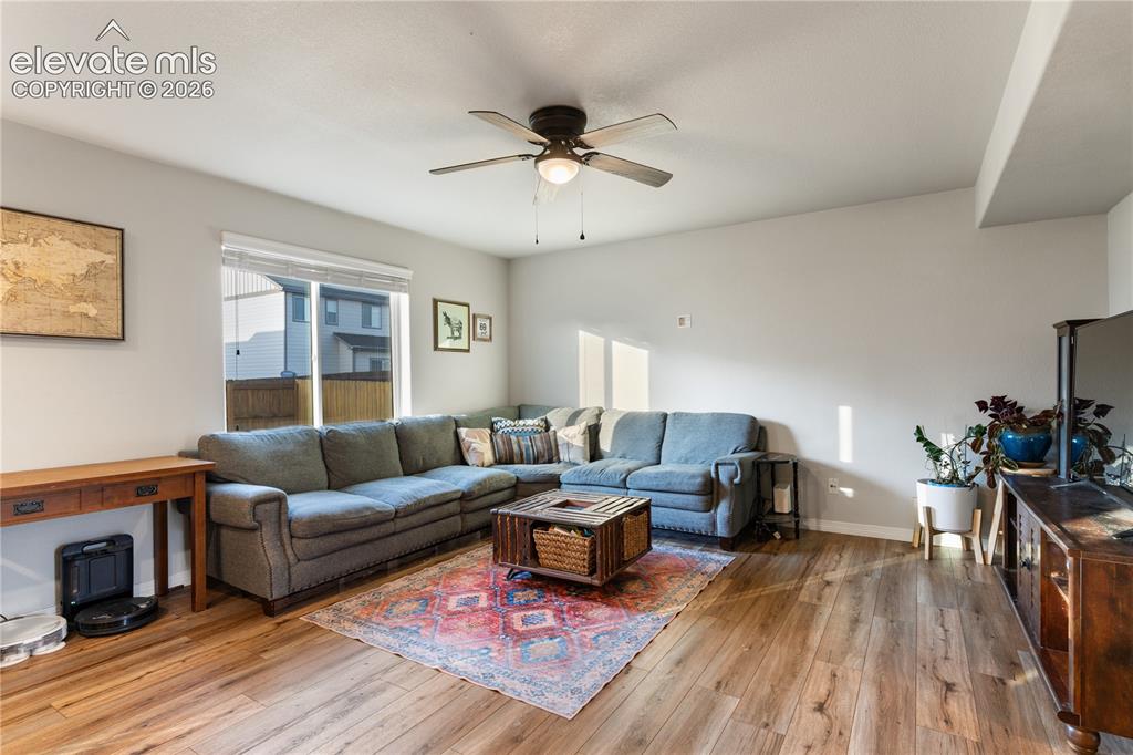Image 11 of 43: Spacious living area featuring wood-finish flooring, a ceiling fan with int