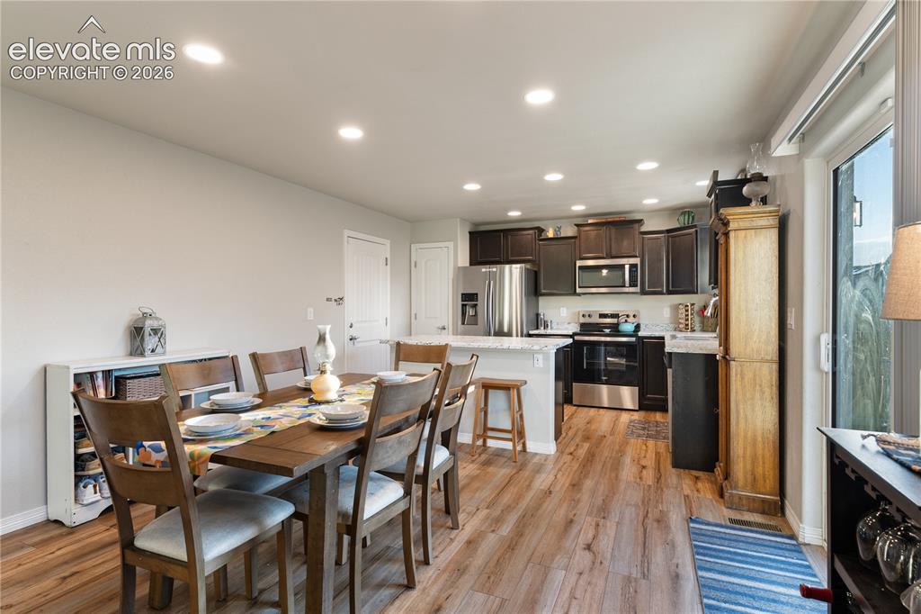 Image 16 of 43: Open-concept dining area featuring wood-finish flooring, recessed lighting,