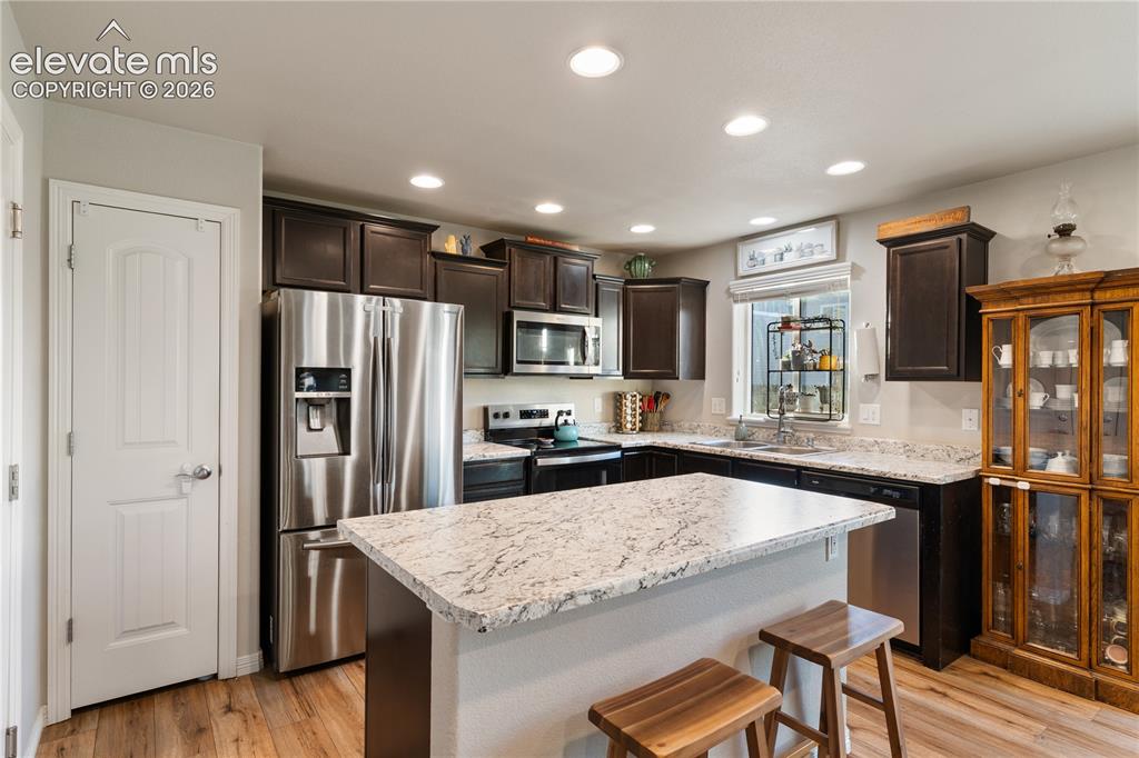 Image 17 of 43: Kitchen featuring a central island with a light-toned countertop, dark wood
