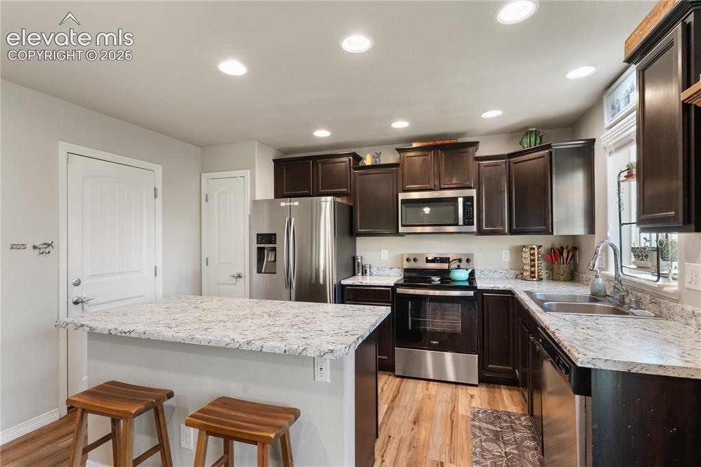 Image 19 of 43: Kitchen featuring dark wood cabinetry stainless steel appliances and a pant