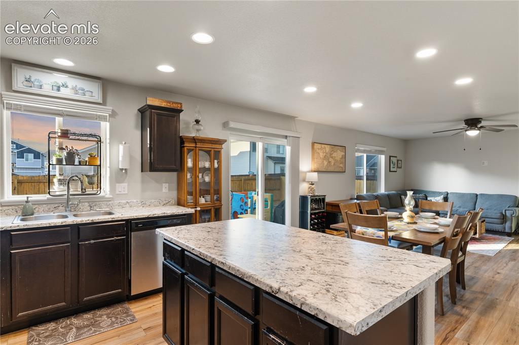 Image 20 of 43: Open-concept kitchen featuring dark wood cabinetry, granite countertops, an