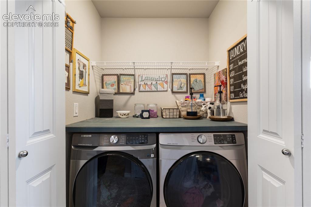 Image 25 of 43: Dedicated laundry area featuring a countertop surface, wire shelving, and o