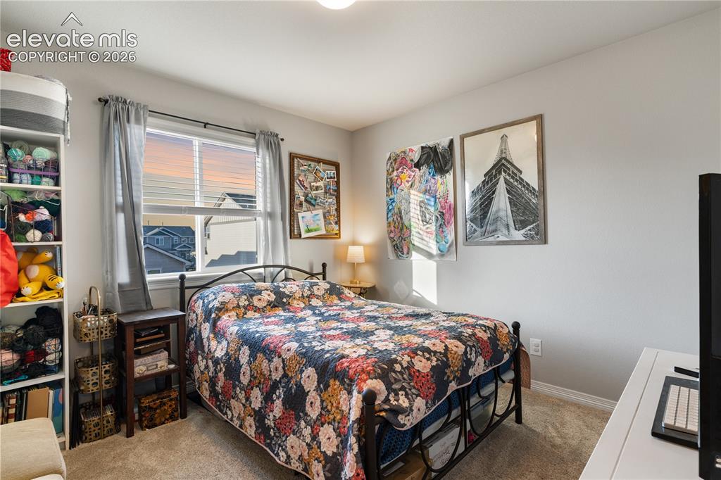 Image 32 of 43: Carpeted bedroom with a window featuring blinds and light-filtering curtain