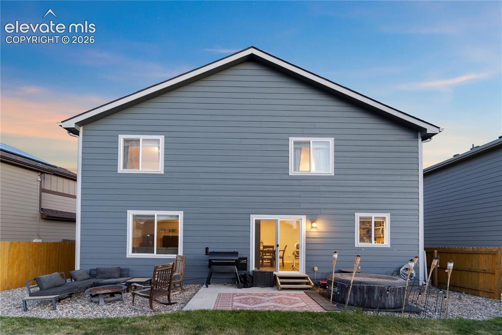 Image 40 of 43: Rear exterior with blue horizontal siding, white trim, and a patio area