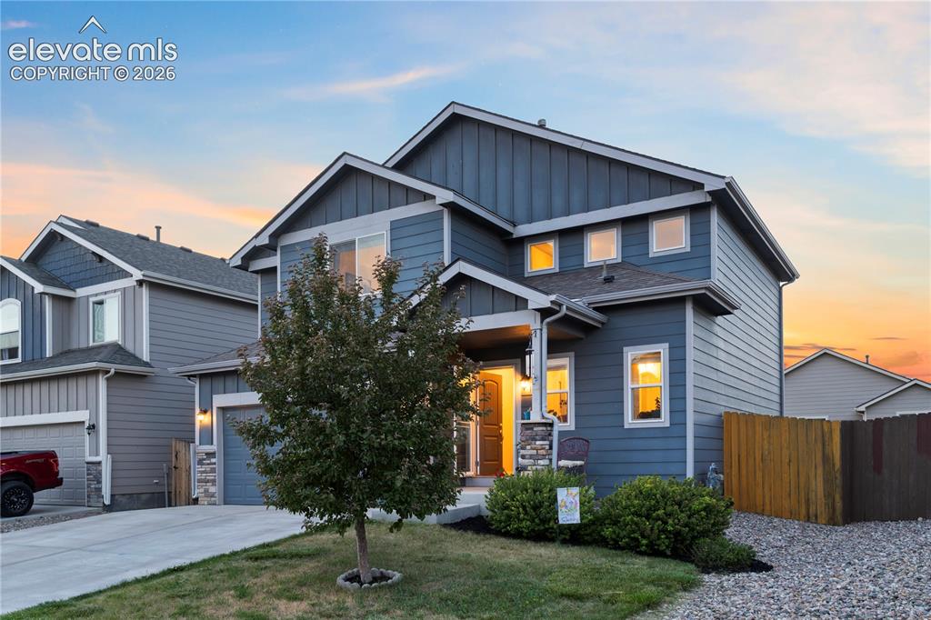 Image 7 of 43: Multi-level residence featuring blue siding, a stone accent column, a cover