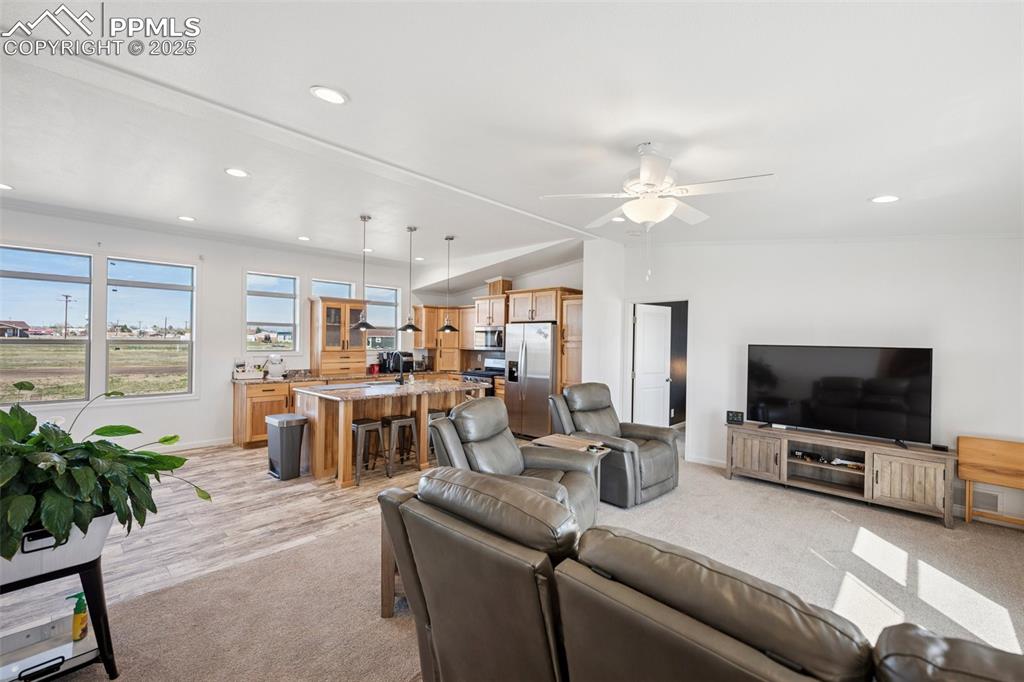 Image 13 of 34: Living area featuring light carpet, baseboards, ceiling fan, recessed light