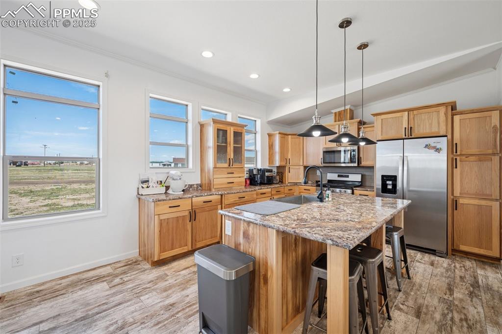 Image 15 of 34: Kitchen with a kitchen island with sink, a kitchen bar, a sink, light wood-