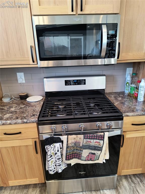 Image 20 of 34: Kitchen featuring tasteful backsplash, dark stone counters, light brown cab