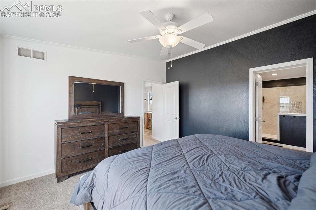 Image 24 of 34: Bedroom featuring ensuite bathroom, ornamental molding, carpet, and visible