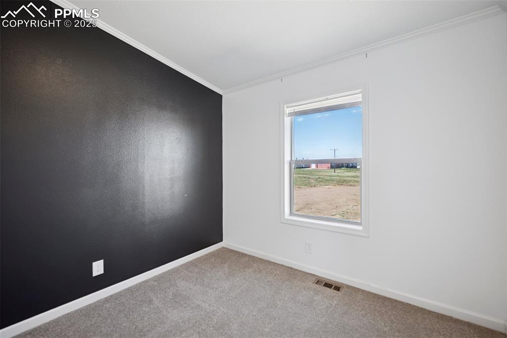Image 30 of 34: Carpeted guest bedroom room with crown molding, baseboards, and visible ven