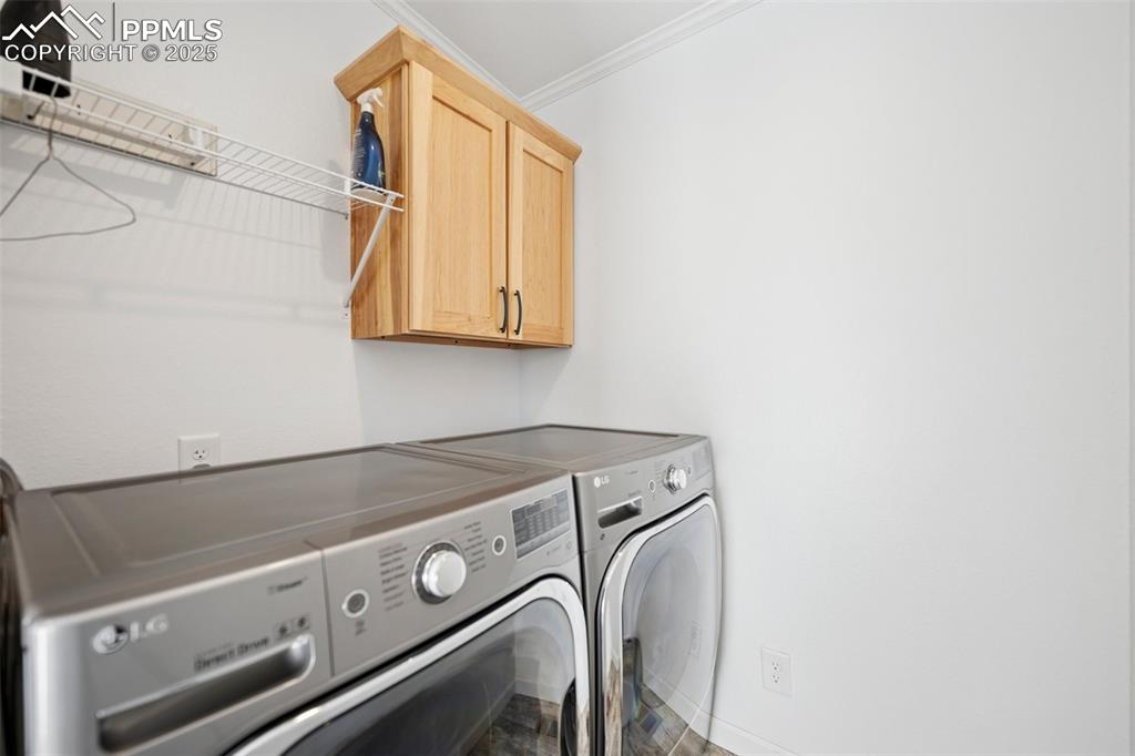 Image 33 of 34: Washroom with ornamental molding, cabinet space, and washer and clothes dry