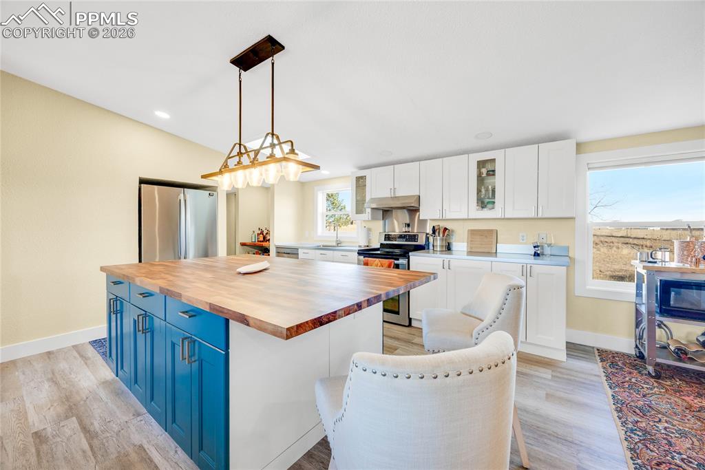 Image 11 of 49: Kitchen with blue cabinets, stainless steel appliances, a kitchen island, w