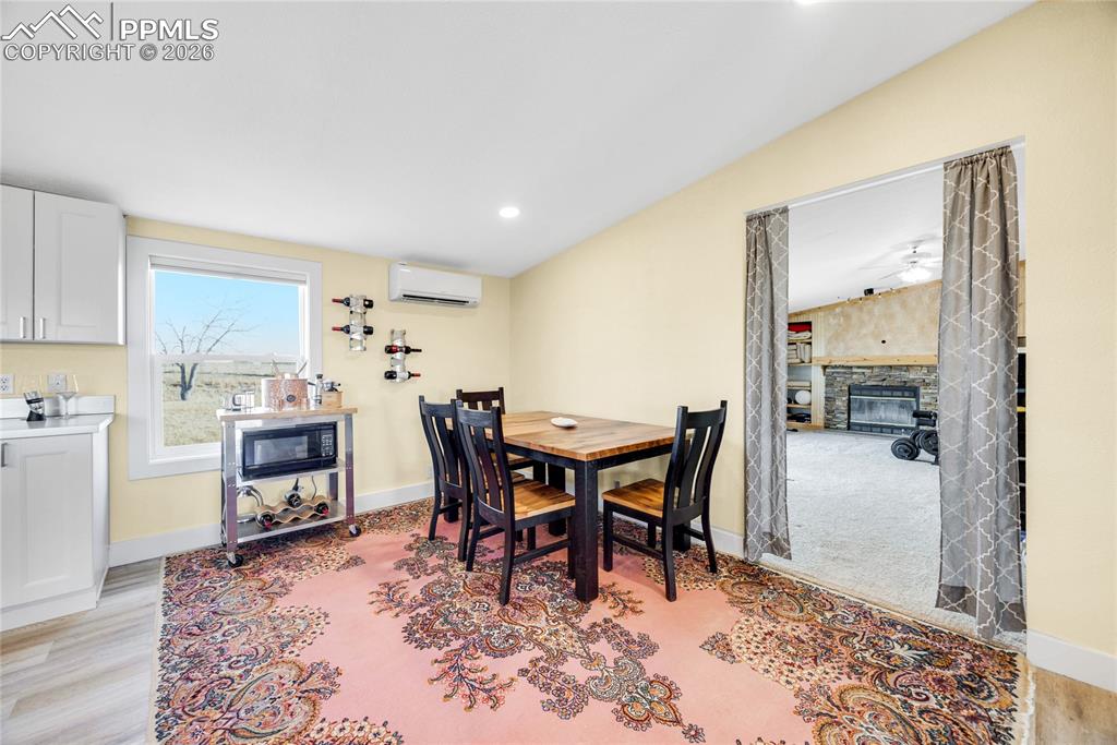 Image 12 of 49: Dining space with a stone fireplace, recessed lighting, light wood-type flo