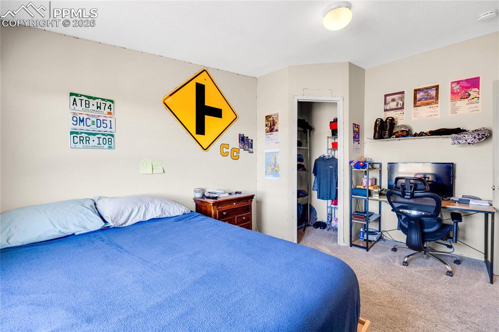 Image 30 of 49: Bedroom featuring a walk in closet, light carpet, and an office area