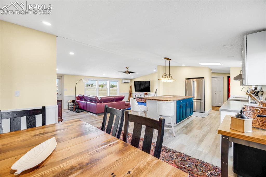 Image 7 of 49: Dining area with light wood finished floors, a ceiling fan, vaulted ceiling