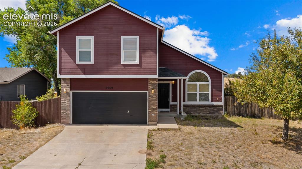 Image 1 of 33: Two-story residence featuring a red siding exterior and a stone-clad founda