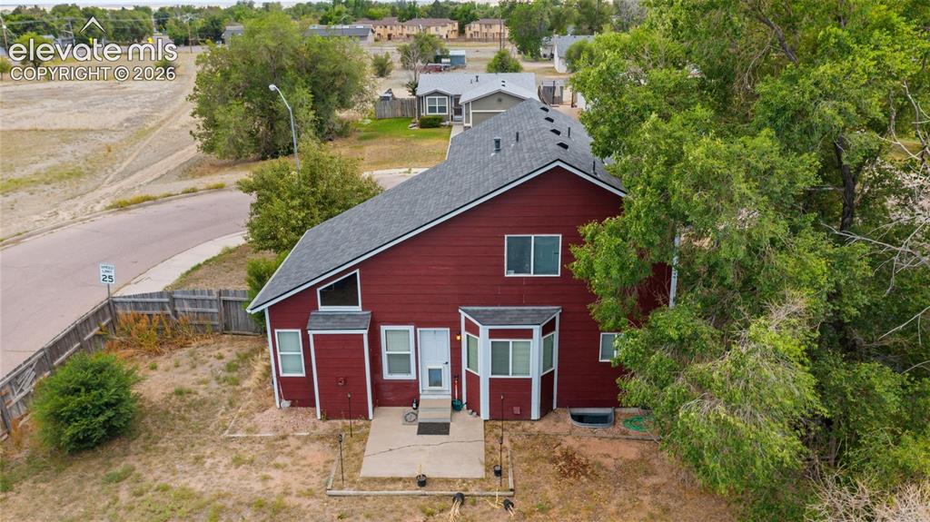 Image 25 of 33: Rear exterior featuring red siding, a gray shingle roof, multiple windows, 