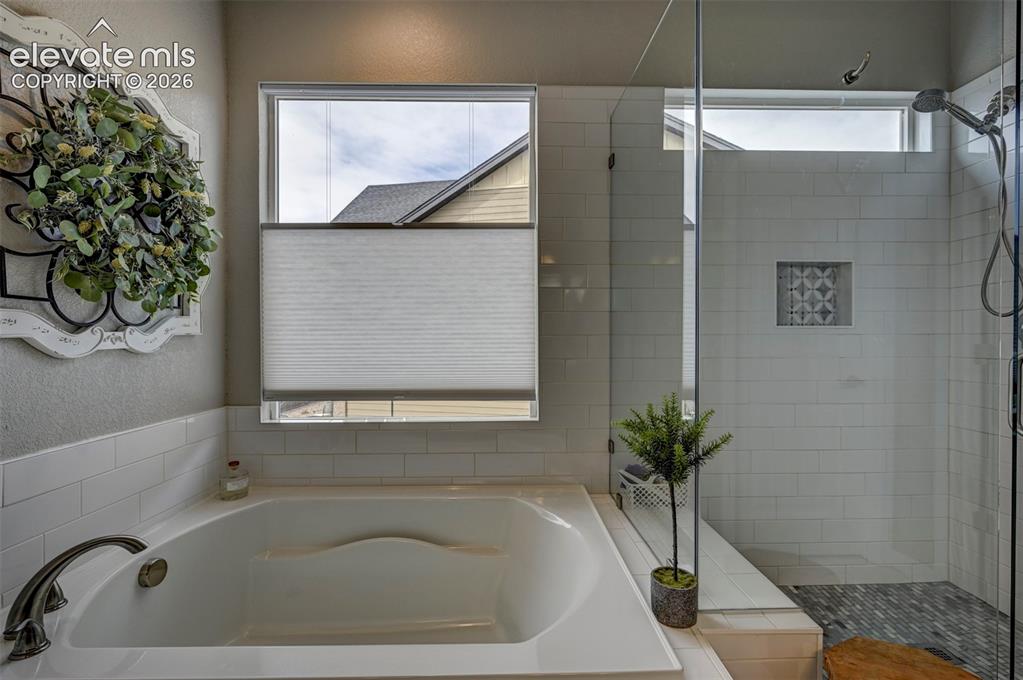 Image 10 of 29: Soaking tub with brushed nickel fixtures, subway tile surround, separate gl