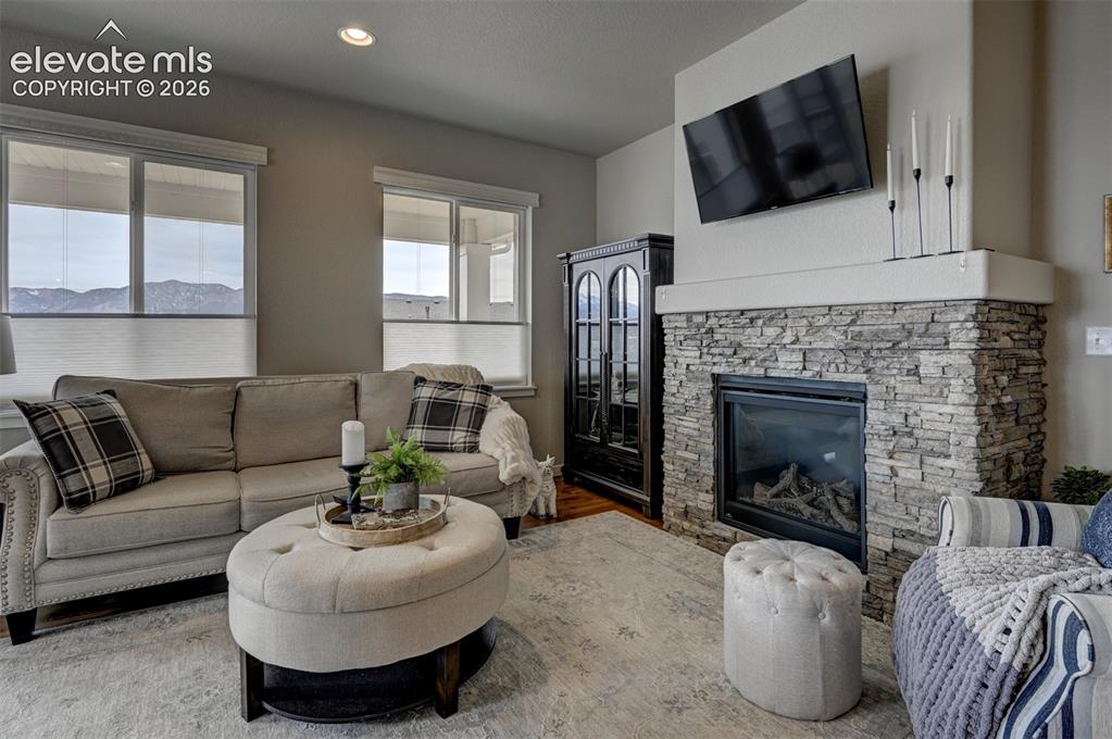 Image 14 of 29: Living area featuring a stacked stone fireplace with a raised hearth, reces