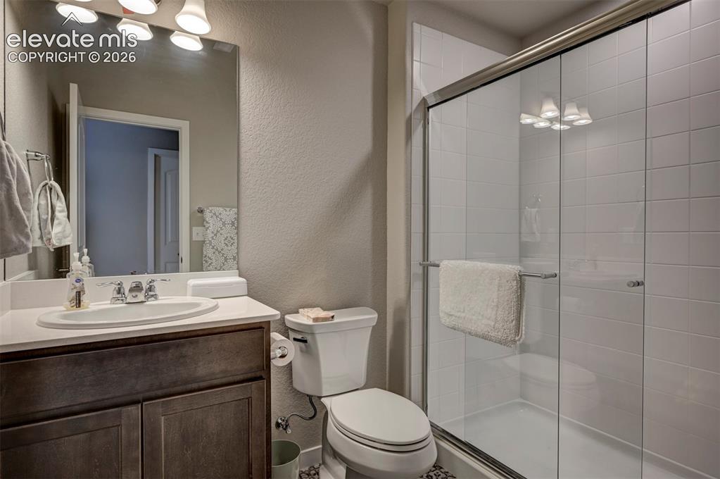 Image 23 of 29: Bathroom featuring a wood-finish vanity, white countertop, oval sink, large