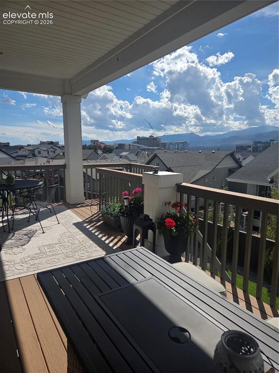 Image 24 of 29: Covered outdoor deck with composite decking, white ceiling, and wooden rail