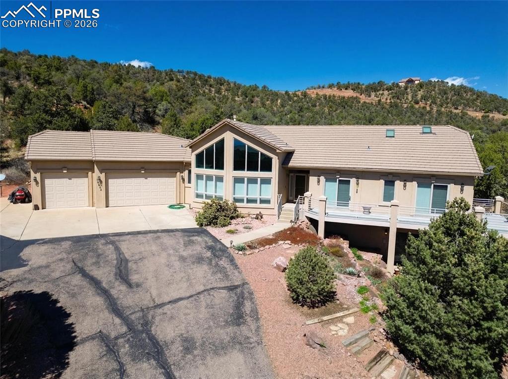 Caption: View of front of home featuring asphalt driveway, an attached garage, stucco siding, and a tile roof