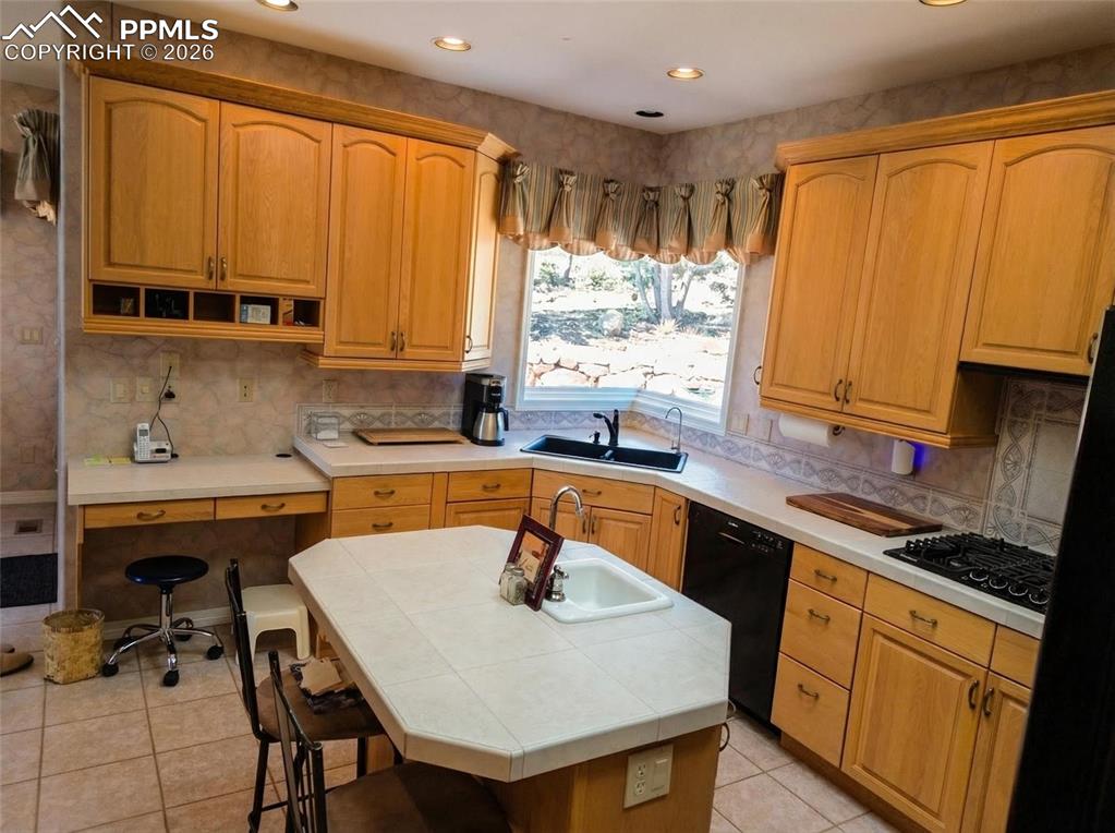 Image 10 of 30: Kitchen featuring a kitchen bar, tasteful backsplash, black appliances, til