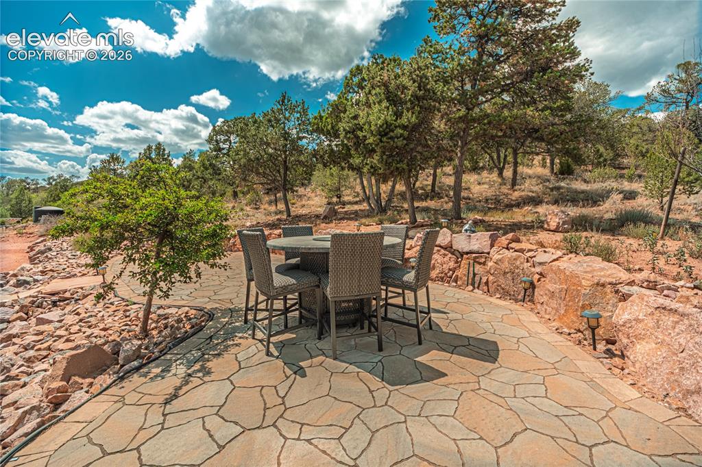 Image 10 of 50: Expansive flagstone patio with natural rock landscaping and mature trees