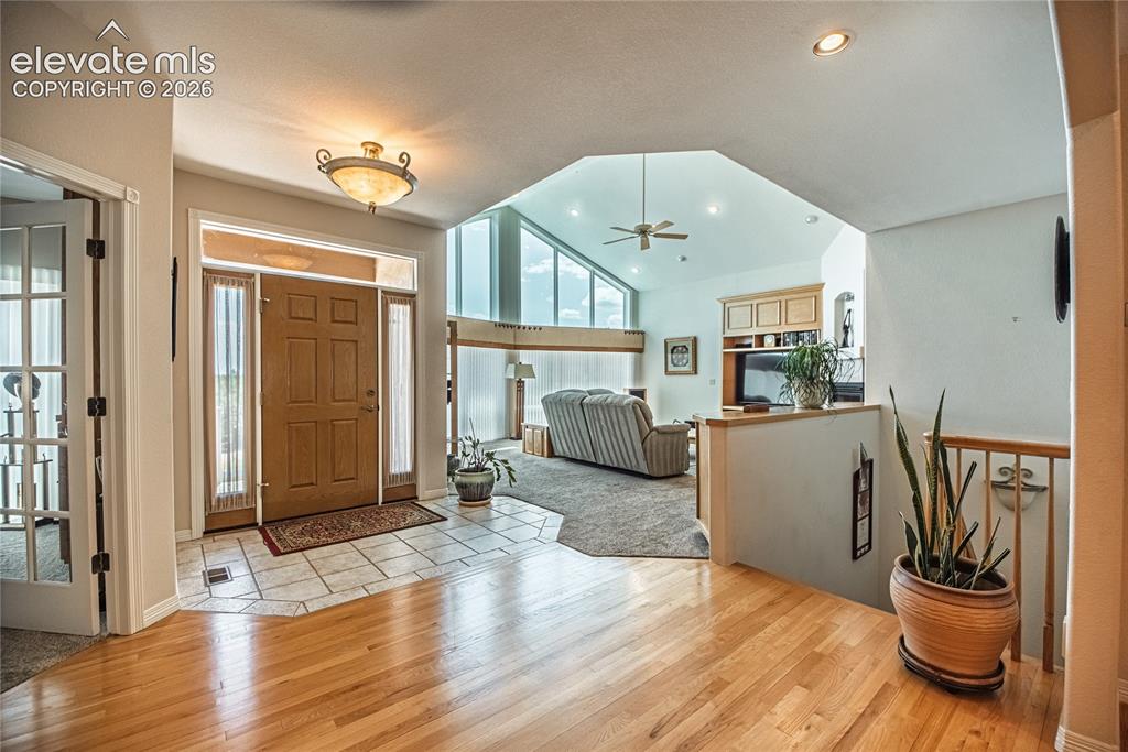 Image 13 of 50: Foyer featuring a paneled wood entry door with sidelights and transom, tile