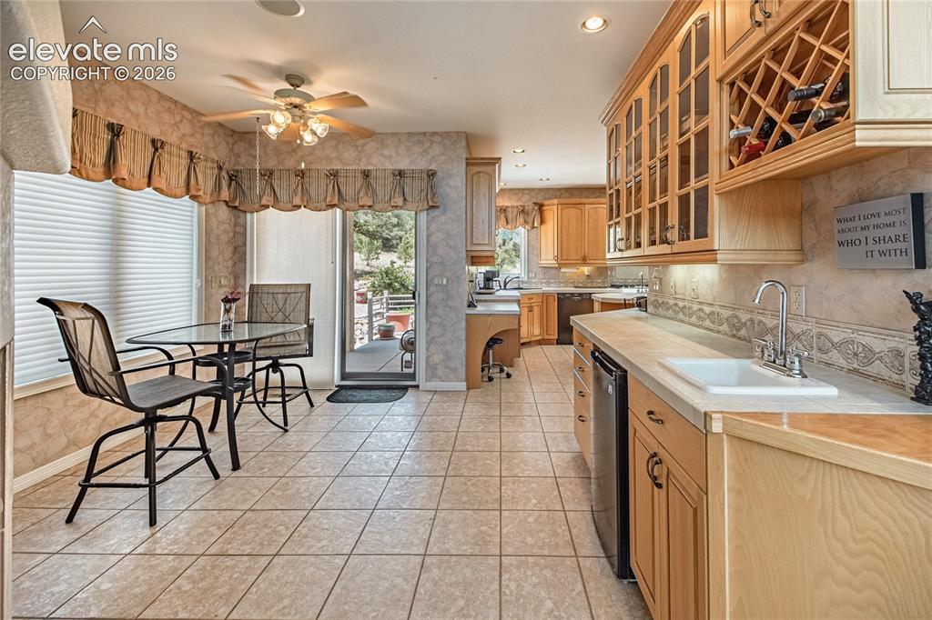 Image 17 of 50: Kitchen with light wood cabinetry, tiled flooring, and a stainless steel un
