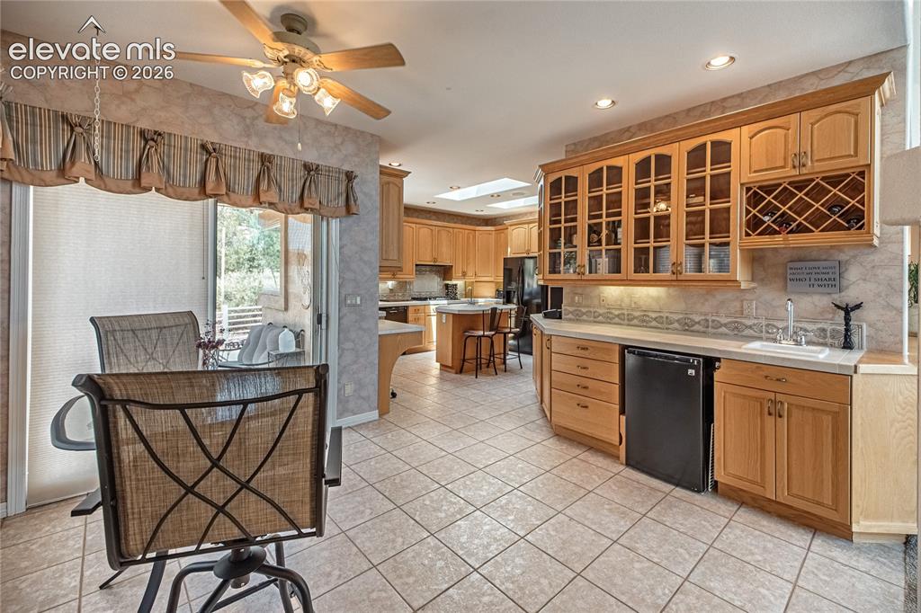 Image 18 of 50: Open-concept kitchen and dining area featuring light wood cabinetry, a buil