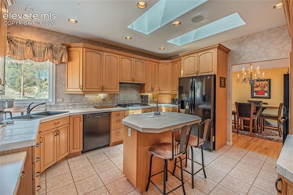 Image 20 of 50: Kitchen featuring light wood cabinetry, stone-finish countertops, and tile