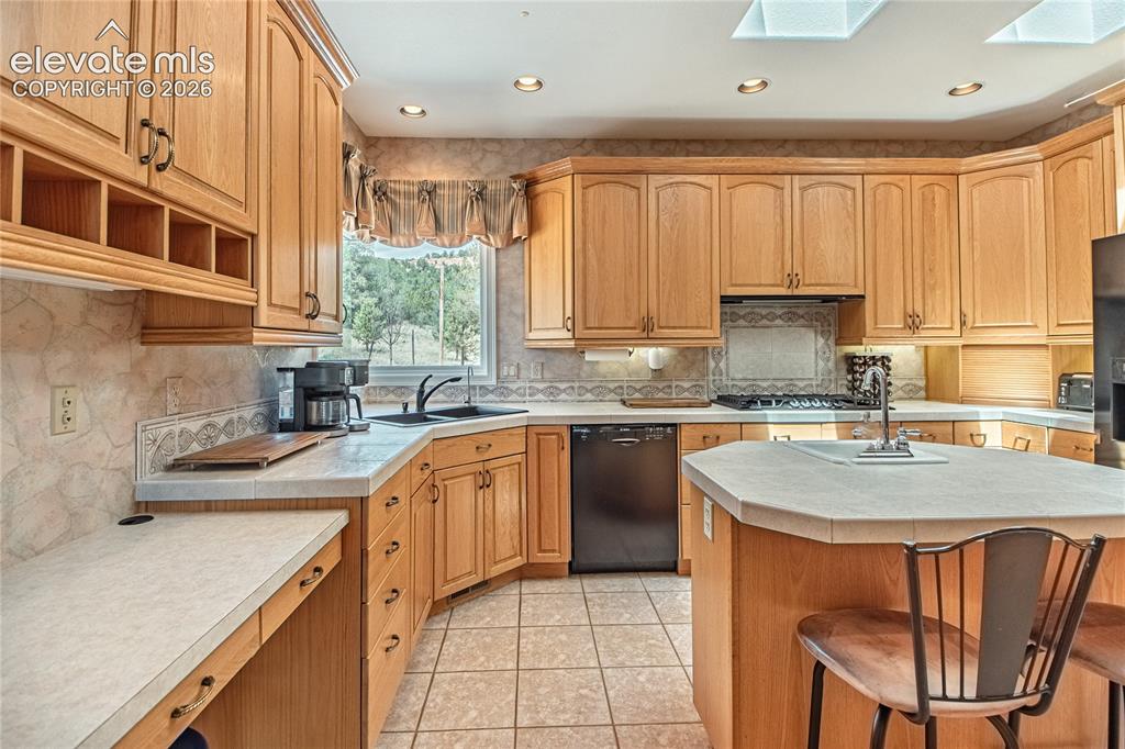 Image 21 of 50: Kitchen featuring abundant wood cabinetry, an island with seating, a gas co