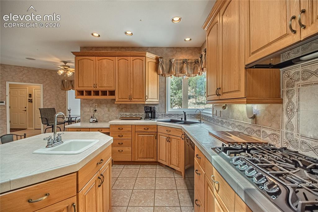 Image 22 of 50: Kitchen featuring light wood cabinetry, a central island with an integrated