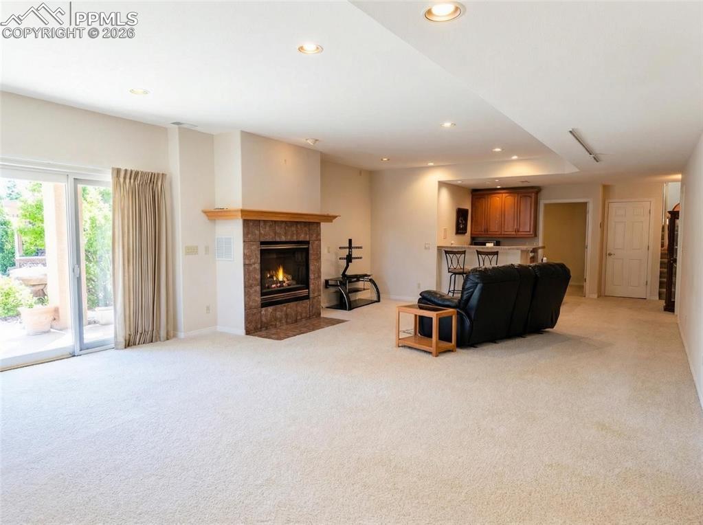 Image 24 of 30: Living area featuring light colored carpet, a tiled fireplace, and recessed
