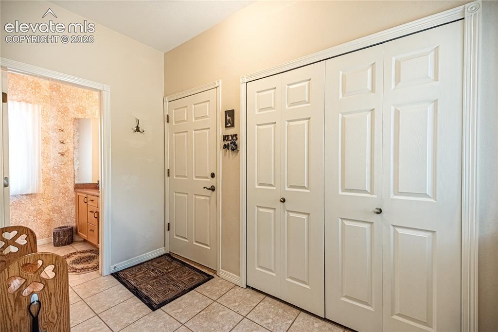 Image 24 of 50: Entryway featuring tile flooring, a paneled door, and two bifold closet doo