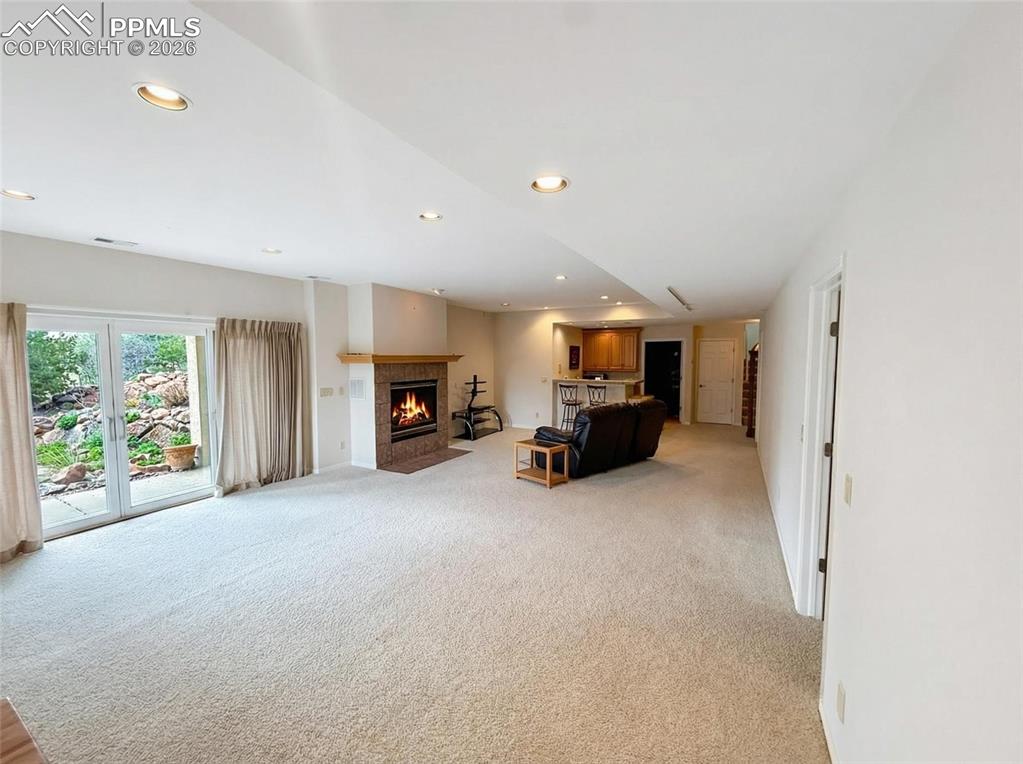 Image 25 of 30: Living area featuring a fireplace with flush hearth, light carpet, and rece