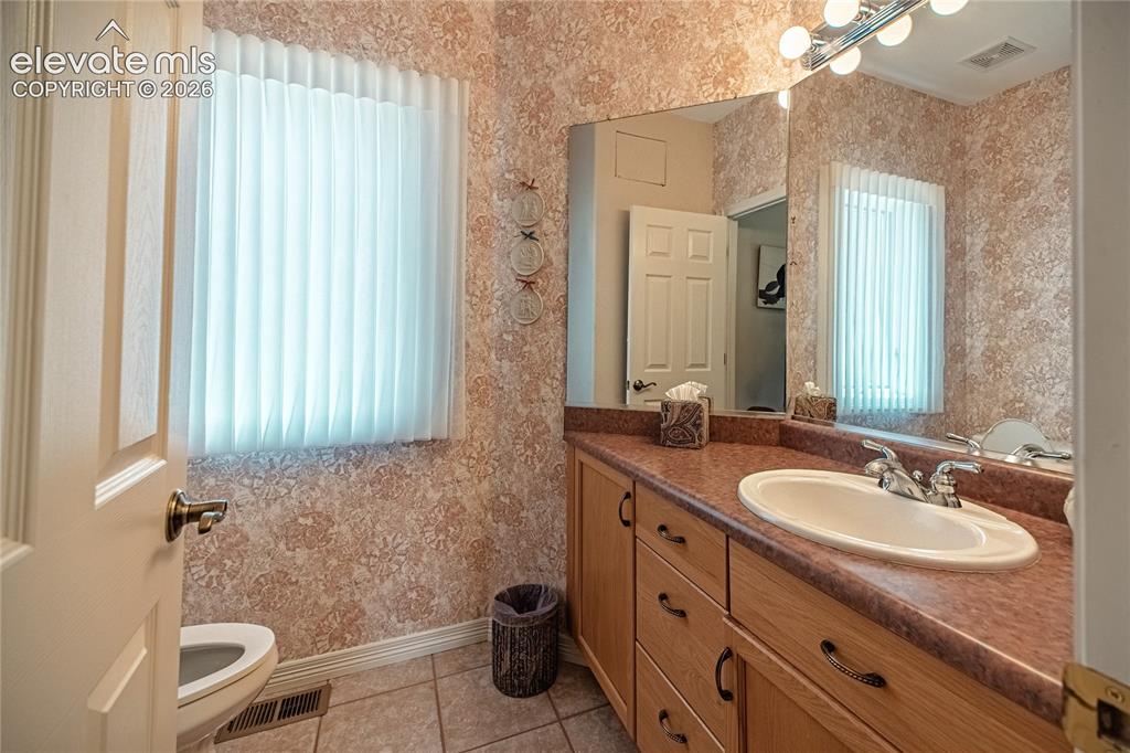 Image 25 of 50: Vanity with an integrated white sink, dual-handle faucet, and expansive wal